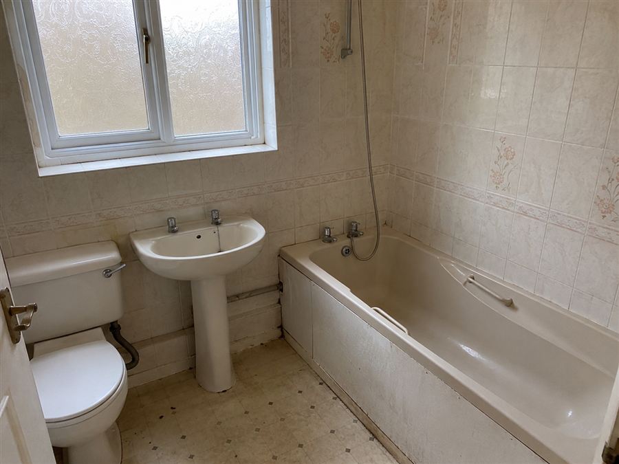 Bathroom before renovation — dated tiles and old suite